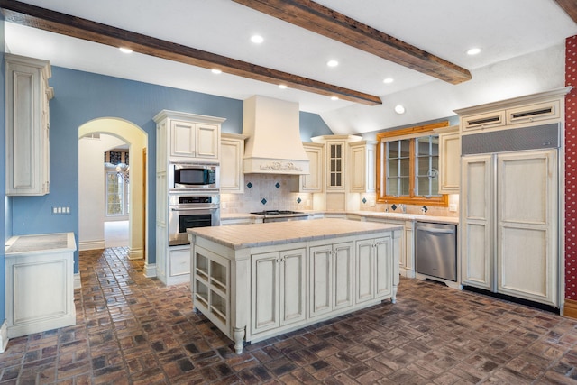4156 E Division St, Springfield, MO 65802 - kitchen with built in appliances, custom exhaust hood, a kitchen island, arched walkways, and backsplash