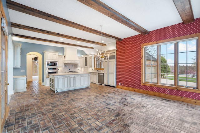 4156 E Division St, Springfield, MO 65802 - kitchen with appliances with stainless steel finishes, premium range hood, wallpapered walls, cream cabinets, and arched walkways
