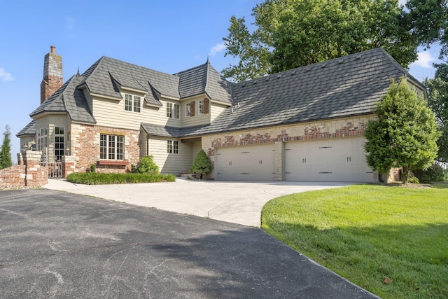 4156 E Division St, Springfield, MO 65802 - view of front of home with an attached garage, concrete driveway, a chimney, a front lawn, and a high end roof