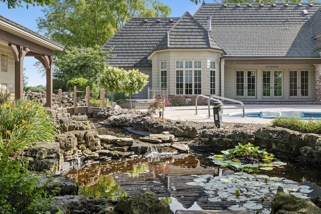 4156 E Division St, Springfield, MO 65802 - back of property featuring french doors, a patio area, an outdoor pool, a small pond, and a hot tub
