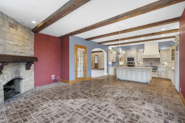 4156 E Division St, Springfield, MO 65802 - unfurnished living room with arched walkways, brick flooring, beamed ceiling, a fireplace, and recessed lighting