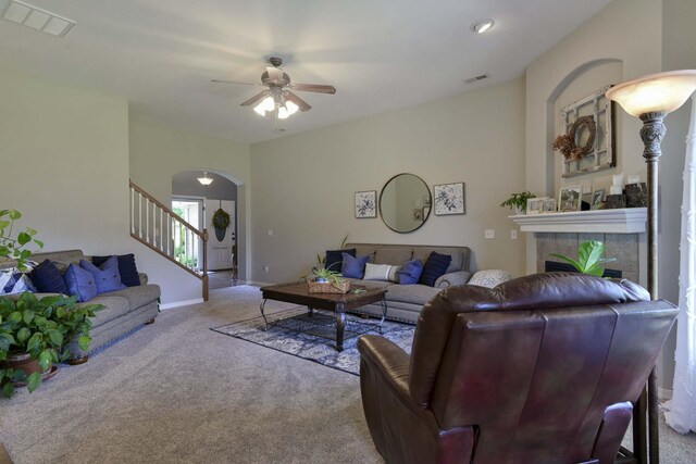 105 Deer Run, Willard, MO 65781 - living area featuring arched walkways, carpet flooring, ceiling fan, a tiled fireplace, and stairs