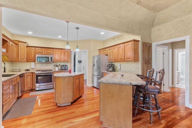3702 E Dartmoor Ct, Springfield, MO 65802 - kitchen featuring appliances with stainless steel finishes, a breakfast bar, light wood-style flooring, a peninsula, and light stone counters