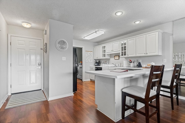 161 Avondale Dr Unit 1, Branson, MO 65616 - kitchen with a kitchen bar, dark wood-style flooring, light countertops, a peninsula, and glass insert cabinets