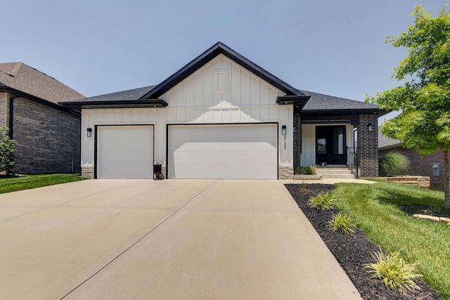 3733 E Hutcheson Ave, Springfield, MO 65802 - view of front of house with board and batten siding, a garage, driveway, a front yard, and stone siding