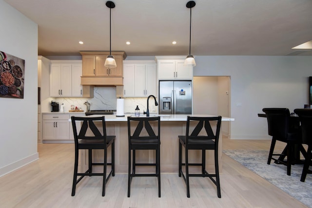 3733 E Hutcheson Ave, Springfield, MO 65802 - kitchen with stainless steel fridge, light wood-style flooring, backsplash, an island with sink, and light countertops