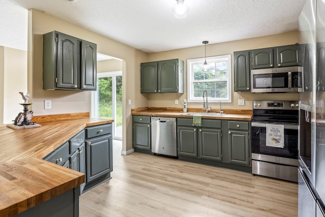 3936 S 77th Rd, Dunnegan, MO 65640 - kitchen featuring wooden counters, appliances with stainless steel finishes, light wood finished floors, a textured ceiling, and hanging light fixtures