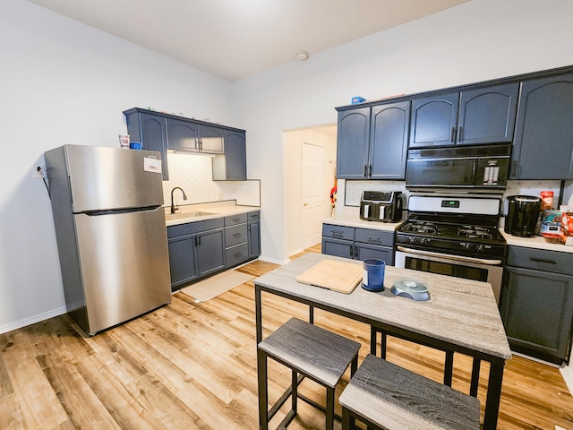 1305 N Main Ave, Springfield, MO 65802 - kitchen featuring stainless steel appliances, tasteful backsplash, light countertops, and light wood-style flooring