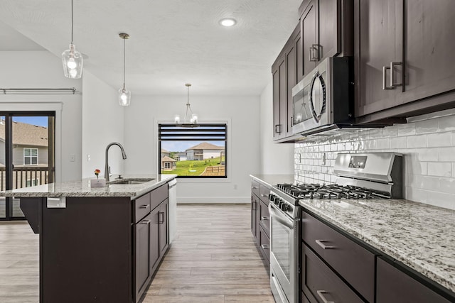 1305 W Ragweed Ct, Ozark, MO 65721 - kitchen featuring appliances with stainless steel finishes, tasteful backsplash, light wood finished floors, light stone countertops, and dark brown cabinetry