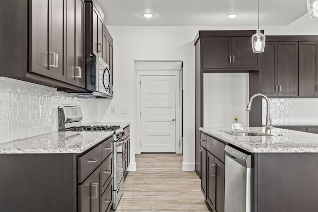 1305 W Ragweed Ct, Ozark, MO 65721 - kitchen with stainless steel appliances, dark brown cabinetry, light wood finished floors, and recessed lighting