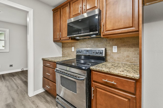 7047 W Lone Oak St, Springfield, MO 65803 - kitchen with stainless steel appliances, backsplash, wood finished floors, light stone countertops, and brown cabinets