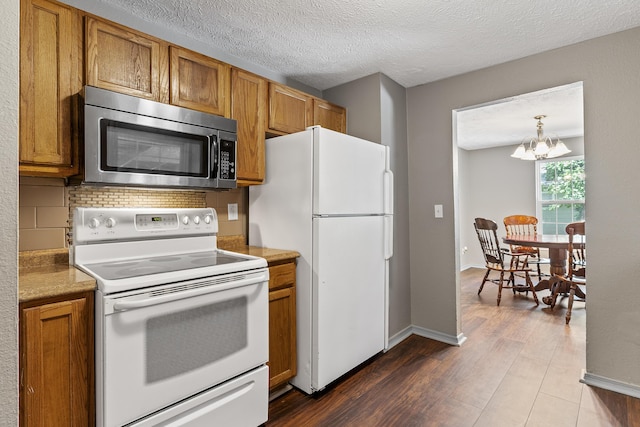 922 W Elm St, Springfield, MO 65806 - kitchen with white appliances, brown cabinetry, a chandelier, dark wood-style flooring, and a textured ceiling