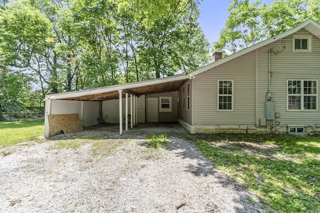 922 W Elm St, Springfield, MO 65806 - view of front of property with gravel driveway, an attached carport, and a chimney