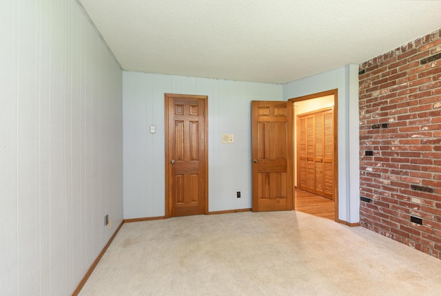 424 W Olive St, Bolivar, MO 65613 - unfurnished bedroom with light colored carpet, a textured ceiling, and brick wall