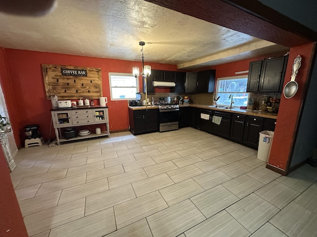 3200 Driftwood Rd, Merriam Woods, MO 65740 - kitchen featuring stainless steel range with gas cooktop, under cabinet range hood, light countertops, a textured ceiling, and pendant lighting