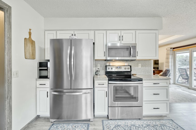 202 N Harper Ave, Springfield, MO 65802 - kitchen with stainless steel appliances, white cabinetry, light wood-style flooring, a textured ceiling, and light countertops