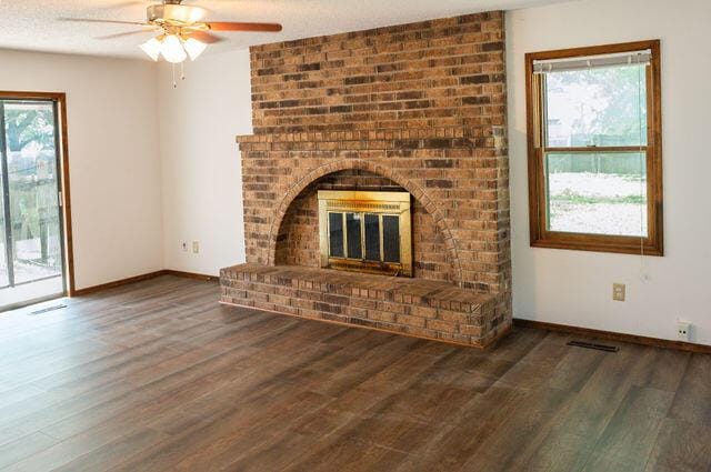 2812 W Maplewood St, Springfield, MO 65807 - unfurnished living room featuring wood finished floors, ceiling fan, and a brick fireplace