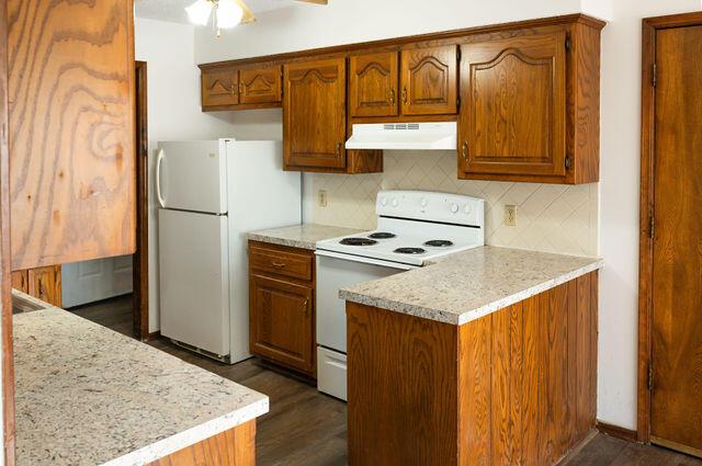 2812 W Maplewood St, Springfield, MO 65807 - kitchen featuring under cabinet range hood, white appliances, backsplash, and dark wood finished floors