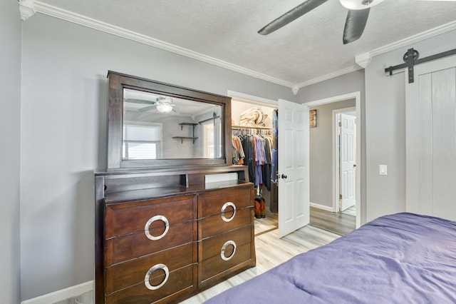 3153 W Washita St, Springfield, MO 65807 - bedroom with ornamental molding, light wood-type flooring, a textured ceiling, a ceiling fan, and a barn door