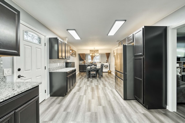 3153 W Washita St, Springfield, MO 65807 - kitchen featuring freestanding refrigerator, light wood finished floors, a chandelier, hanging light fixtures, and light stone counters