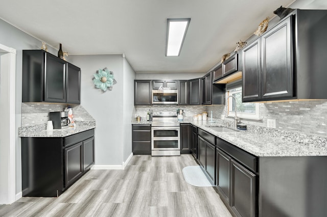 3153 W Washita St, Springfield, MO 65807 - kitchen featuring appliances with stainless steel finishes, light wood-type flooring, tasteful backsplash, and light stone countertops