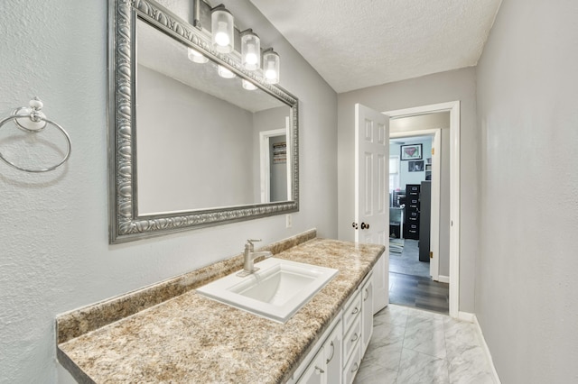 3153 W Washita St, Springfield, MO 65807 - bathroom featuring marble finish flooring, vanity, a textured ceiling, and a textured wall
