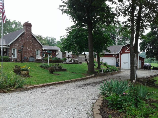 701 Spears Ave, Crane, MO 65633 - view of front of home with driveway, a front yard, an outdoor structure, brick siding, and a chimney