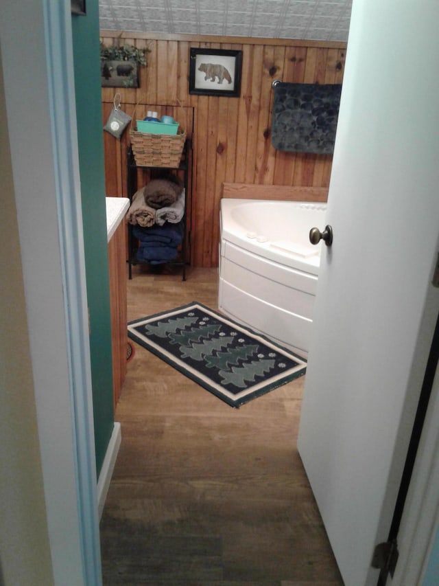 701 Spears Ave, Crane, MO 65633 - bathroom featuring vanity, wood finished floors, wooden walls, and a tub to relax in
