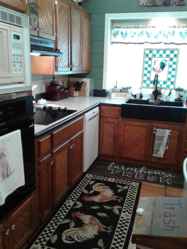 701 Spears Ave, Crane, MO 65633 - kitchen with black appliances, under cabinet range hood, and brown cabinets