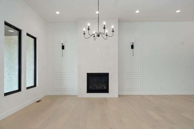 2124 N Silver Charm Ave, Springfield, MO 65802 - unfurnished living room with light wood finished floors, a chandelier, a glass covered fireplace, and recessed lighting