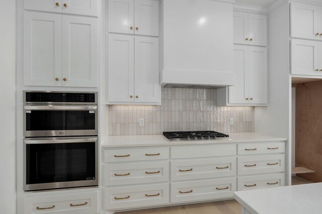 2124 N Silver Charm Ave, Springfield, MO 65802 - kitchen with appliances with stainless steel finishes, wall chimney exhaust hood, tasteful backsplash, light countertops, and white cabinetry