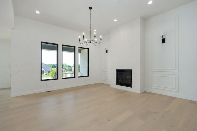2124 N Silver Charm Ave, Springfield, MO 65802 - unfurnished living room with light wood-style flooring, a chandelier, recessed lighting, and a glass covered fireplace