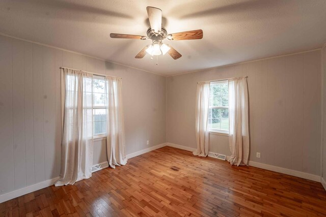 600 E Boone St, Ash Grove, MO 65604 - spare room with wood-type flooring, ceiling fan, and wood walls