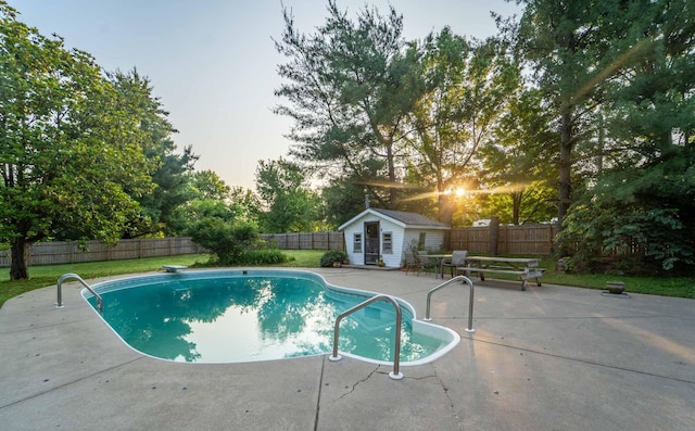 600 E Boone St, Ash Grove, MO 65604 - pool at dusk featuring a patio area, an outdoor structure, a fenced backyard, and view of scattered trees