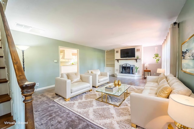 600 E Boone St, Ash Grove, MO 65604 - living room featuring wood finished floors, a fireplace with raised hearth, and stairs