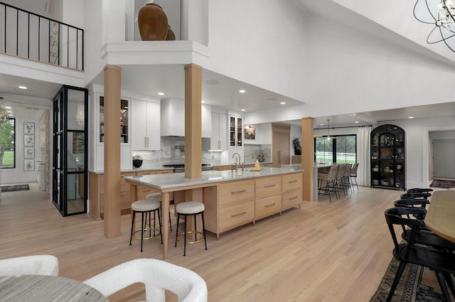 12451 State Highway 174, Billings, MO 65610 - kitchen featuring ornate columns, a high ceiling, light wood-style floors, light countertops, and glass insert cabinets