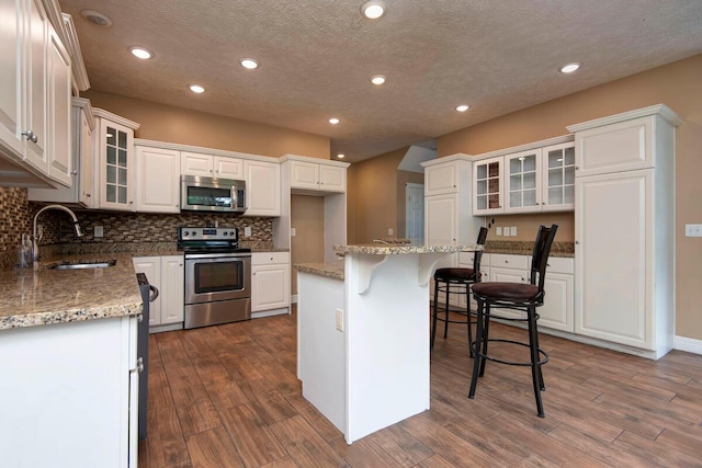 1108 N 18th Ave, Ozark, MO 65721 - kitchen with stainless steel appliances, dark wood-style flooring, white cabinetry, recessed lighting, and tasteful backsplash