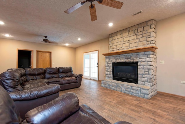 1108 N 18th Ave, Ozark, MO 65721 - living room featuring a textured ceiling, wood finished floors, a ceiling fan, a stone fireplace, and recessed lighting