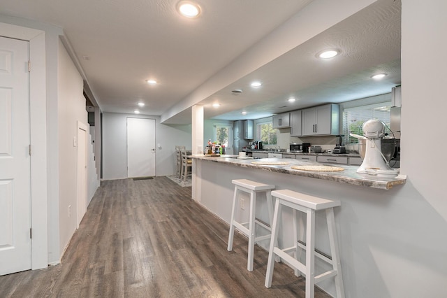 2225 N Plainview Ave, Springfield, MO 65803 - kitchen featuring dark wood finished floors, a peninsula, gray cabinets, recessed lighting, and a kitchen breakfast bar