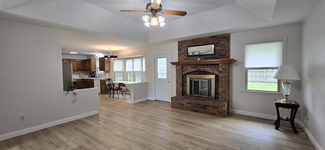 2782 W Swan St, Springfield, MO 65807 - living area with plenty of natural light, a tray ceiling, a brick fireplace, and light wood-style floors