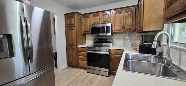 2782 W Swan St, Springfield, MO 65807 - kitchen with appliances with stainless steel finishes, light wood finished floors, tasteful backsplash, light countertops, and brown cabinets