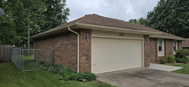2782 W Swan St, Springfield, MO 65807 - view of side of home with driveway, brick siding, an attached garage, and a gate