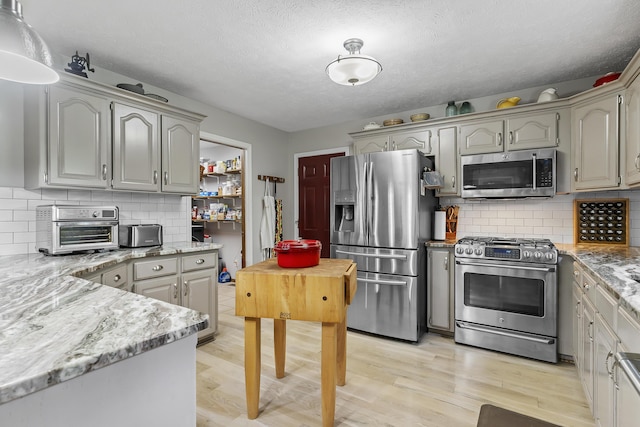 11996 N Farm Rd Unit 119, Brighton, MO 65617 - kitchen with appliances with stainless steel finishes, light wood-type flooring, tasteful backsplash, light stone counters, and a textured ceiling