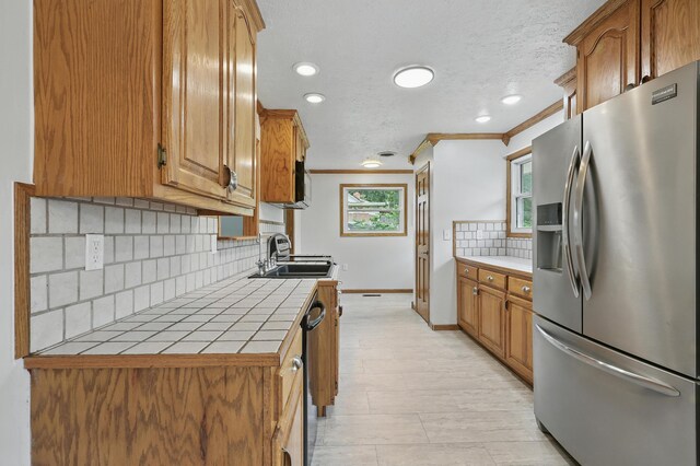 14289 Bethel Rd, Seneca, MO 64865 - kitchen with stainless steel fridge, tile countertops, ornamental molding, tasteful backsplash, and plenty of natural light