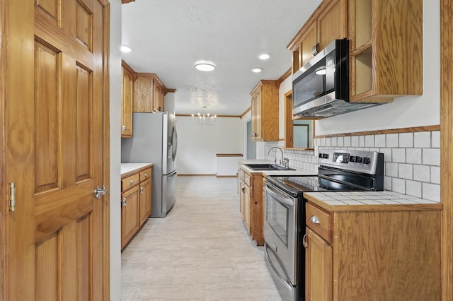 14289 Bethel Rd, Seneca, MO 64865 - kitchen featuring stainless steel appliances, tile counters, a chandelier, backsplash, and brown cabinetry