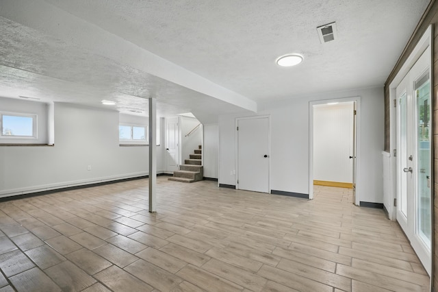 14289 Bethel Rd, Seneca, MO 64865 - below grade area featuring a textured ceiling, stairway, light wood-type flooring, a baseboard heating unit, and healthy amount of natural light