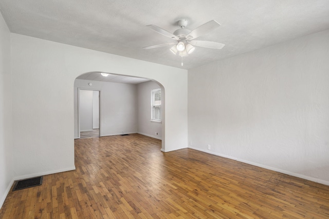 825 W Nichols St, Springfield, MO 65802 - empty room with arched walkways, hardwood / wood-style floors, and a ceiling fan