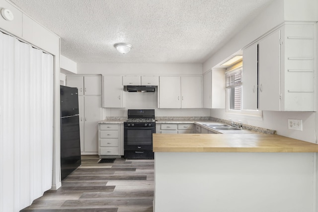 825 W Nichols St, Springfield, MO 65802 - kitchen featuring black appliances, under cabinet range hood, a textured ceiling, a peninsula, and butcher block countertops