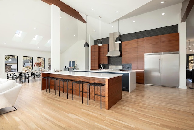 621 S Woodhaven Rd, Nixa, MO 65714 - kitchen with wall chimney exhaust hood, stainless steel built in refrigerator, modern cabinets, high vaulted ceiling, and a kitchen bar