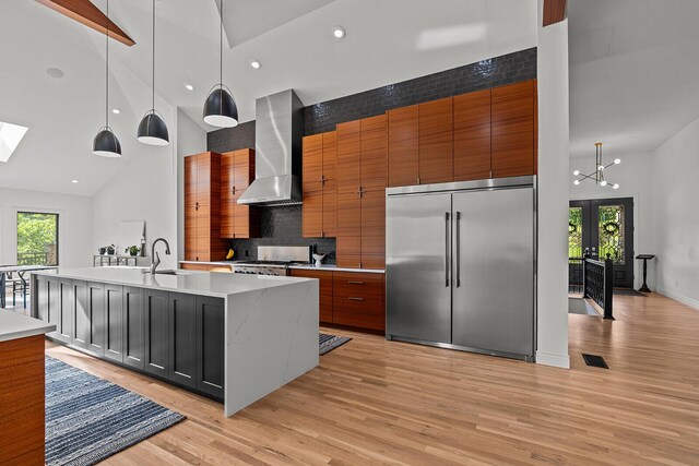621 S Woodhaven Rd, Nixa, MO 65714 - kitchen with stainless steel built in refrigerator, wall chimney exhaust hood, high vaulted ceiling, light wood finished floors, and range